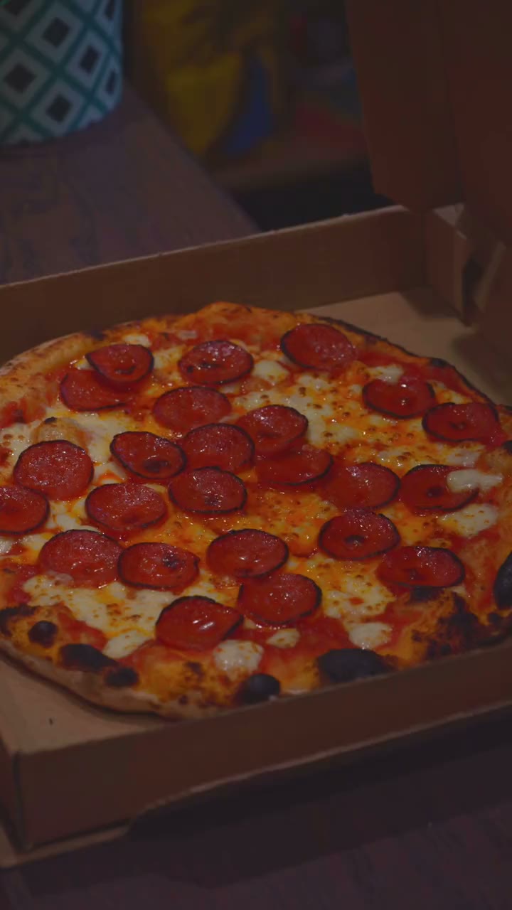 A pepperoni pizza just out of the wood-fired oven, filmed close up